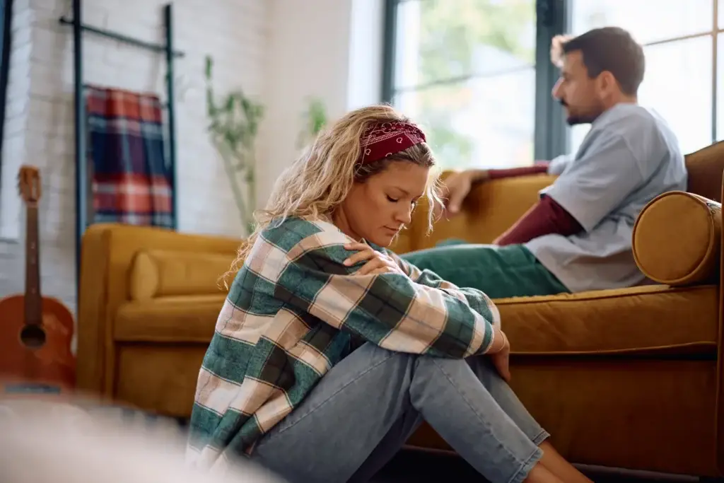 Couple sitting at opposite ends of a couch, distance between them in the relationship