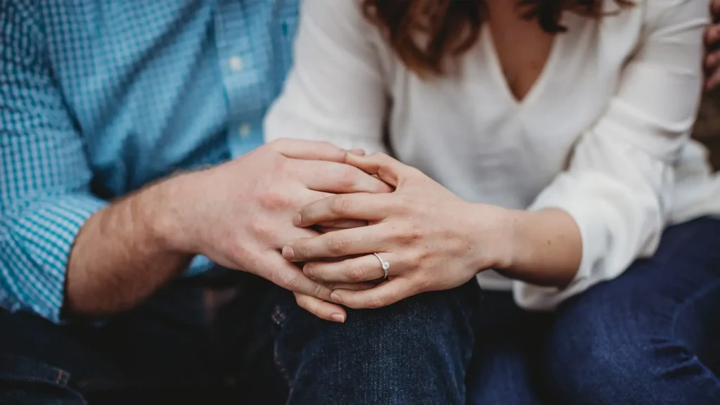 Couple sitting closely with clasped hands, illustrating recurring relationship conflict