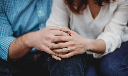 Couple sitting closely with clasped hands, illustrating recurring relationship conflict